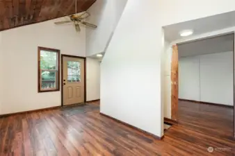 Enter into the open plan living room/dining/kitchen with vaulted ceiling and skylight.  You can see the opening for the stairs going down to the principal bedroom.