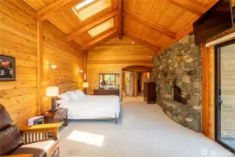 primary bedroom with skylights, fireplace, doors to the deck