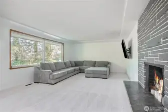 Open large living room with ambient lighting and beautiful fireplace with stone hearth.