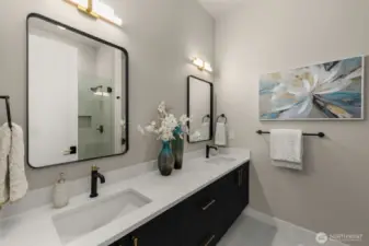 Main floor guest suite bath with dual sinks and framless shower