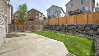 Relax or entertain in this peaceful backyard oasis with brand-new grass, a generous patio space, and a charming rock wall—all enclosed for your privacy and comfort