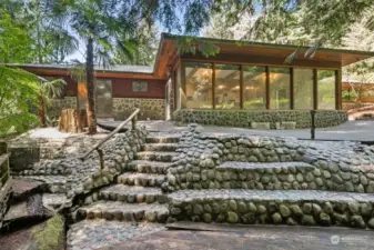 House feels like a mid-century modern, with rustic beams, huge stone fireplaces, stone walkway entry, wall of accent wood and more! Built on hardpan, the house is very sturdy and is in a location on the property that you would not be able to currently build on. Take advantage of the creekside location!
