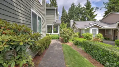 Mature landscaping lines the walk-way to this charming townhome.