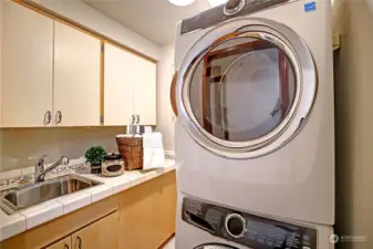 Large laundry room with sink, plenty of storage and nice washer/dryer set.