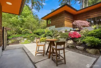 The back patio surrounded by rich, curated gardens.