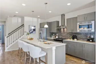 The chef’s kitchen features a gas range, huge quartz island, stainless steel appliances, and quartz countertops!