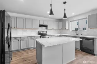 Pendant lighting above the island counter with eating bar in the open concept Kitchen.