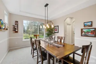 Formal dining room with view toward patios and yard. Doorway on right provides access to walk-in pantry and kitchen.