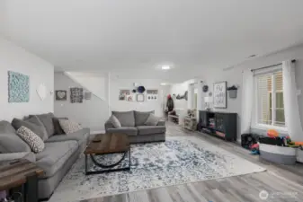 The spacious living room is designed for comfort, featuring large windows, warm finishes, and plenty of space for relaxing or entertaining guests.