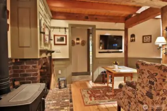 Solid brick hearth with decorative fireplace, another glimpse of the Vermont Casting wood stove. Let's walk through that doorway to the Primary Suite and Laundry Room.