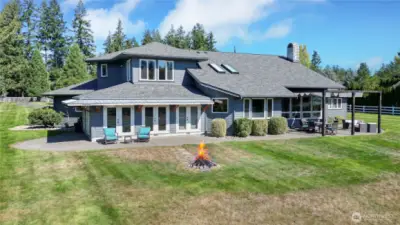 Drone view of the rear of the home. Upstairs is your expansive primary suite overlooking your back acres. I love the huge patio, the skylights and we have had so many amazing fires in that firepit. Just magical!