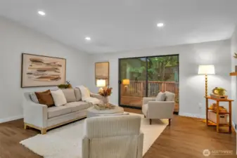 The large slider opens to a deck and back yard surrounded by trees.