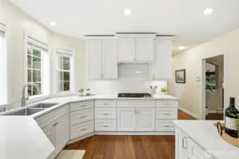 Bright eat-in kitchen with expansive windows overlooking the private wooded setting and Lake Wilderness views, offering seamless indoor-outdoor connection.