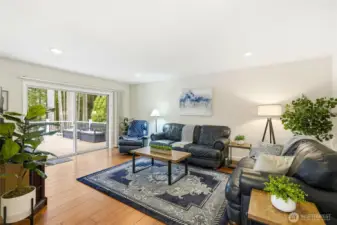 Spacious living room with fireplace, bamboo flooring, and large windows bringing in natural light and scenic Lake Wilderness views.