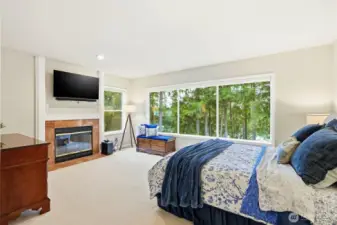 Spacious primary suite with large picture window capturing serene Lake Wilderness and territorial views, plush carpeting, and cozy fireplace creating a true Maple Valley retreat.