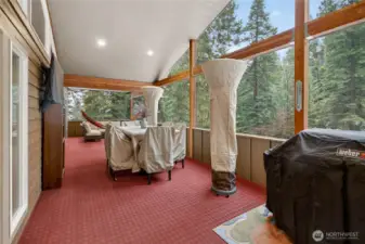 Expansive screened-in porch with two freestanding heaters, a tabletop fire pit and an affixed flat screen TV.