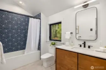 Upstairs full bath with stylish blue tile surround, bathtub, and radiant heated floor.
