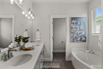 An expansive quartz counter provides a space for dual vanities and a place to store bathroom essentials with ease. A water closet just steps away offers privacy in this shared space.