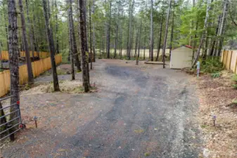 This cleared and level lot offers a gravel driveway leading to a spacious area between mature trees, providing privacy and a peaceful atmosphere. Ready for RV use or future development. A storage shed is located toward the back for added convenience, and the fencing enhances privacy.