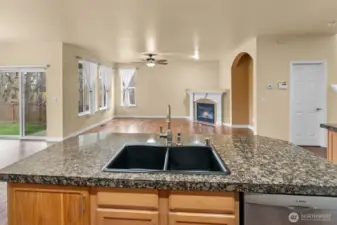 A durable composite sink set in granite, overlooking the open living area and fireplace