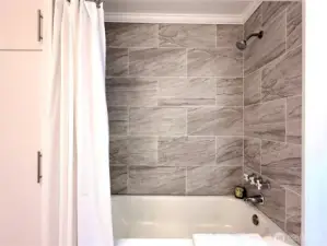 Storage to left of shower tub with beautiful new tile