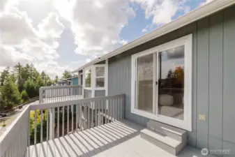 The back side of the home with the decks off the dining room and kitchen and another deck off the primary bedroom.