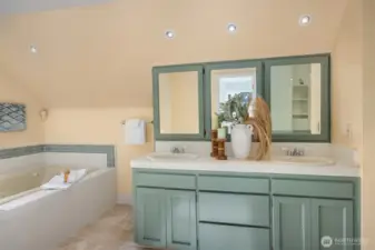 Dual vanities in a calming muted green palette, enhanced by abundant natural light at the mirrors—an inviting space to start the day.