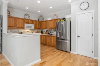 Kitchen as seen from living room. Natural light added with small windows over cabinets. Visible door is pantry with doorway to the right accessing laundry room and garage beyond.