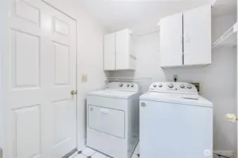 The utility room is off of the garage and has storage, hanging racks, and a cubby hole for more storage to the right.