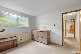 Another view of the second bedroom looking toward the hall with the full bath and the primary suite beyond.