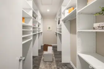 Huge walk in closet in primary suite with custom shelving.