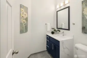 Powder room off of mud room has waterfall quartz countertops.