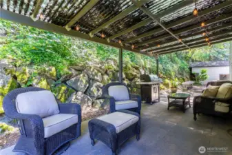 Immediately outside the kitchen french doors is this idyllic covered patio to enjoy sunny or rainy days, barbecue, etc. Beyond that are long benches waiting for a firepit or table (or combined?) Fiberglas patio awning will be hosed off before closing.