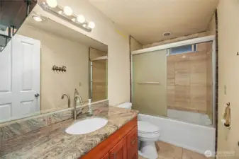 UPDATED HALL BATH  Single vanity with granite counters and backsplash, and under mount sink  Tub with tile surround  Tile floors
