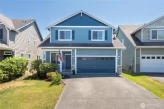 Attractive blue two-story home with mature landscaping and welcoming curb appeal