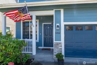 Covered front porch with white railings and welcoming seating area
