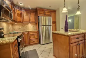 A full tile backsplash in a neutral tone completes the look. The centerpiece of the space is a functional center island. With abundant storage and sleek stainless steel appliances, this kitchen is a perfect blend of style and functionality.