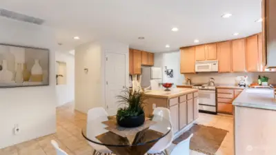 This view captures a close-up of the eating space just off the kitchen, showcasing the kitchen in the background and a nearby entryway that leads to other features of the house.