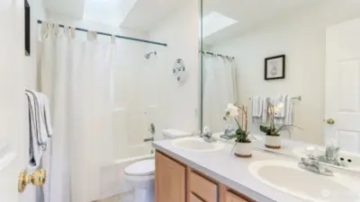 Spacious full guest bathroom upstairs with shower/tub combo and double sink vanity.