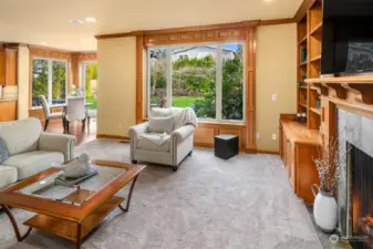 The adjoining family room with fireplace and a wall of built-in shelving.  The surround sound speaker system is provided here, in the kitchen, office, primary bedroom and bonus room.