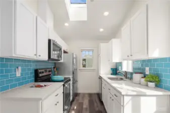 The newly refreshed kitchen features glass tiled backsplash, quartz counters and a skylight.