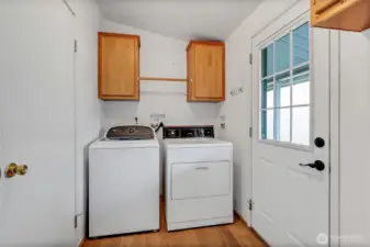 Utility room off the kitchen which includes the washer and dryer. The door to the left is a second entrance to the main hall bath and the door to the right leads outside to the covered walkway to the 2 car garage.