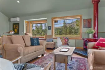 Brilliant living room graced by charming red wood stove adds ambiance and coziness in winter! And check out the   fabulous views from every window!