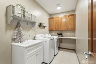 Spacious laundry room off the garage, featuring a utility sink, folding counter and plenty of storage.