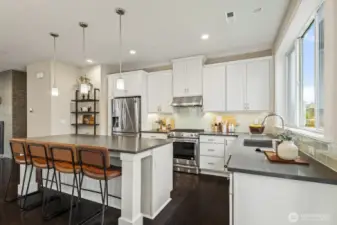 The chef-inspired kitchen showcases a stunning two-tone design, featuring bright, crisp white cabinetry contrasted with elegant, dark quartz countertops, creating a timeless and sophisticated look