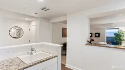 Kitchen opens to entryway and living room, connected with breakfast bar seating