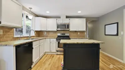 Open kitchen features gorgeous countertops and a perfectly situated island.