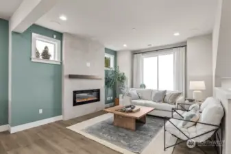 Living room has an electric fireplace for ambiance and surround sound speakers built in the ceiling.