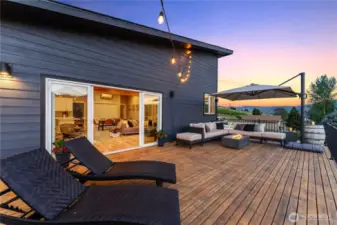 Exterior twilight view of the upper level spacious lake view deck w/ large sliding glass doors off the main living area.