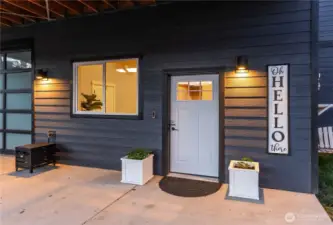 Exterior twilight view of front door & attached garage w/ oversized doors.